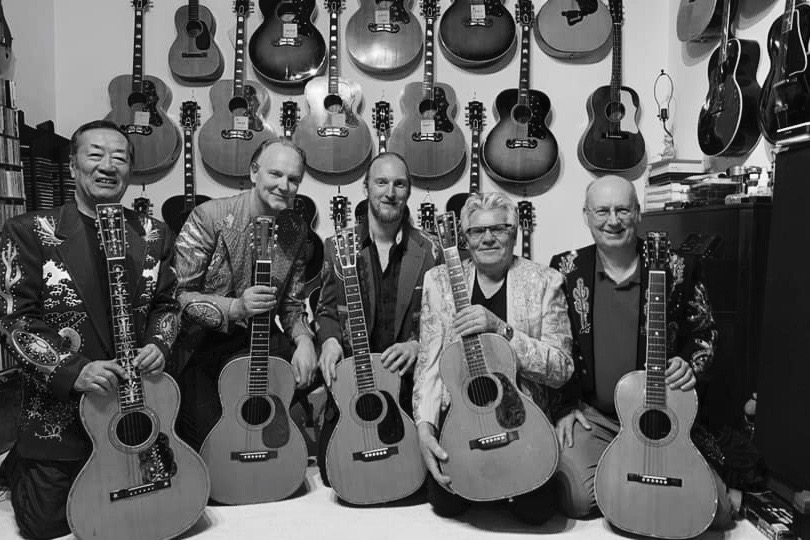 Men holding guitars in a half circle